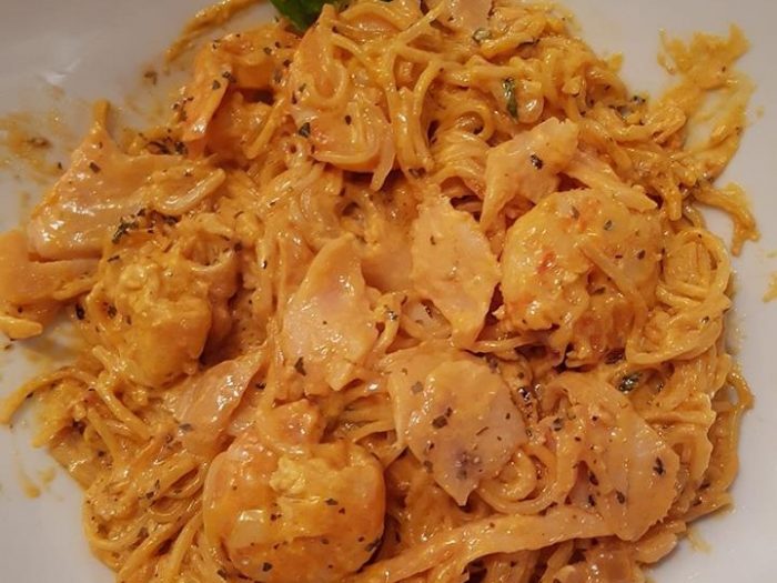 Noodles, shrimps, smoke salmon with a creamy tomato sauce and basil